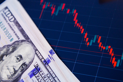 US dollar banknotes over digital screen with exchange chart, depreciation and volatility concept