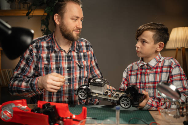 istock Young father teaching his son for soldering electrical car at home. Man and boy fixing broken toy. 1841758658