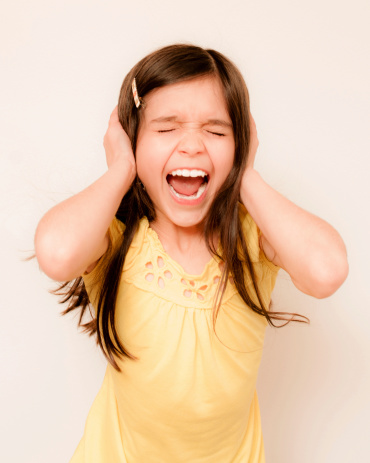 Little girl screaming with hands over ears.