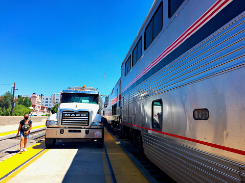 Albuquerque, New Mexico, USA - July 31, 2020: A woman walks past a fuel truck waiting to refuel Amtrak’s Southwest Chief passenger train during a scheduled stop at the Alvarado Transportation Center (ATC) that serves as the city’s Amtrak station.