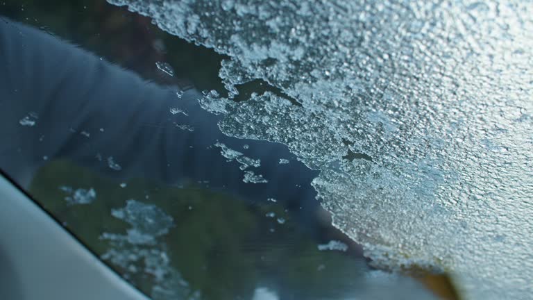 Close up shot of scarping the ice of a car windshield. Freezing rain over night, solid ice layer on the windshield.