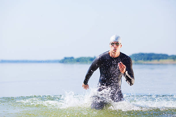 triatleta corriendo fuera del agua - triathlete fotografías e imágenes de stock