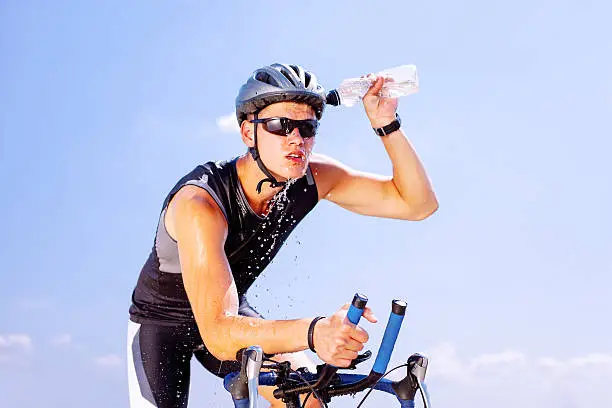 Triathlete cools his head while cycling on a bicycle