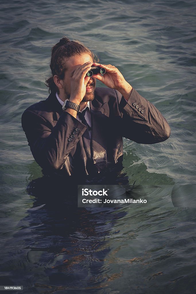 Market Analysis Business in tough times requires reestablishing it's visions. Businessman standing in the Sea looking trough binoculars. Adult Stock Photo