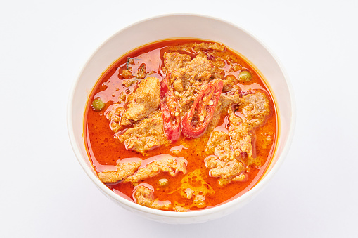 Top view of Panang Curry with Pork top with sliced red chili pepper isolated on white background. Popular Thai food.