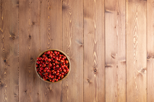 red dog-rose rosehip fruits in a wooden bowl on wooden table