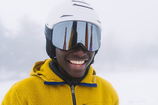 Photo of a young African American with a safety helmet on, getting ready for the slopes