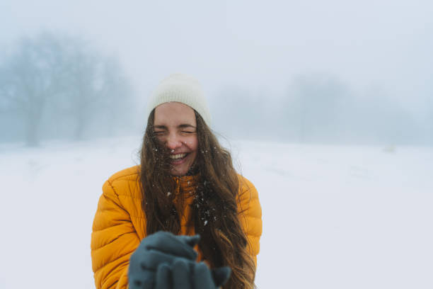 Happy winter time in big city charming girl standing street dressed funny fluffy hat. Enjoying snowfall, expressing positivity, smiling to camera, joyful cheerful mood, true emotions, Christmas mood