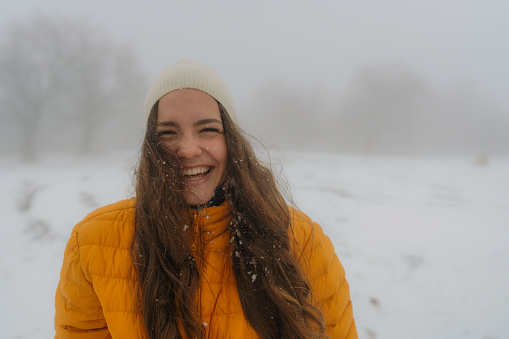 Photo of a young woman who enjoys snow, cold weather and winter activities - having a walk outdoors in a winter wonderland