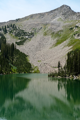 A lake high up in the Rocky Mountains, Utah, reflections of trees visible on the water surface