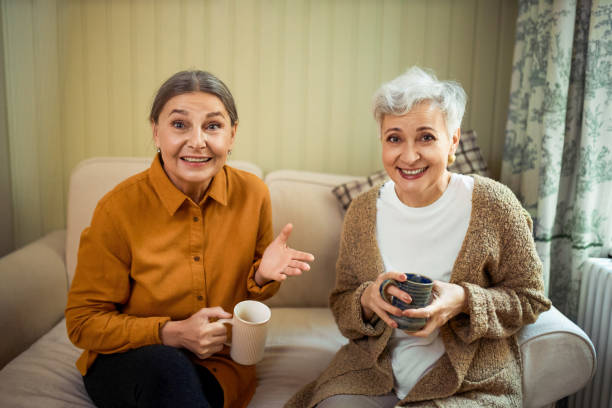 istock Two female pensioners relaxing together, spending nice time on retirement, having coffee after dinner, discussing news, sitting on sofa with mugs in cozy friendly atmosphere. People and lifestyle 1842011804