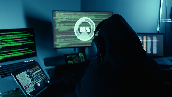 Hacker working on laptop at night in the modern workspace. Hacker or cyber criminal loading transfer data servers systems. Security Breach. Cyber crime, Digital system security