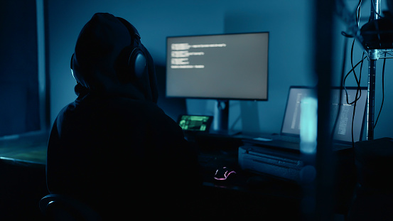 Hacker working on laptop at night in the modern workspace. Hacker or cyber criminal loading transfer data servers systems. Security Breach. Cyber crime, Digital system security