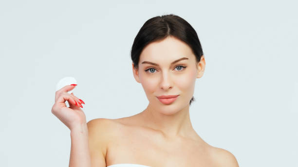 istock Charismatic, beautiful young woman using a cotton pad on a light isolated background. Concept of clean skin, facial care and natural cosmetics. 1842022797