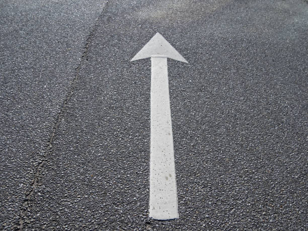 istock A white arrow on black asphalt pointing straight ahead 1842062671