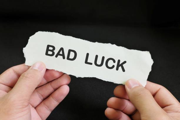 istock Human hand holding a paper note with word Bad Luck in dark black background. 1842082433