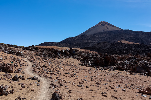 Hiking trail over volcanic desert terrain leading to summit of volcano Pico del Teide, Mount Teide National Park, Tenerife, Canary Islands, Spain, Europe. Solidified lava, ash, pumice along the way
