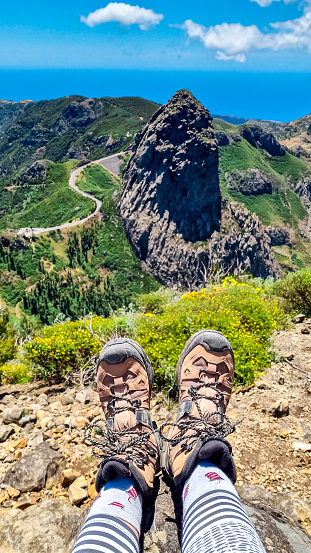 Trekking shoes with scenic view on mountain road next to rock formation Roque de Agando in Garajonay National Park on La Gomera, Canary Islands, Spain,Europe. Seen from lookout Mirador Morro de Agando