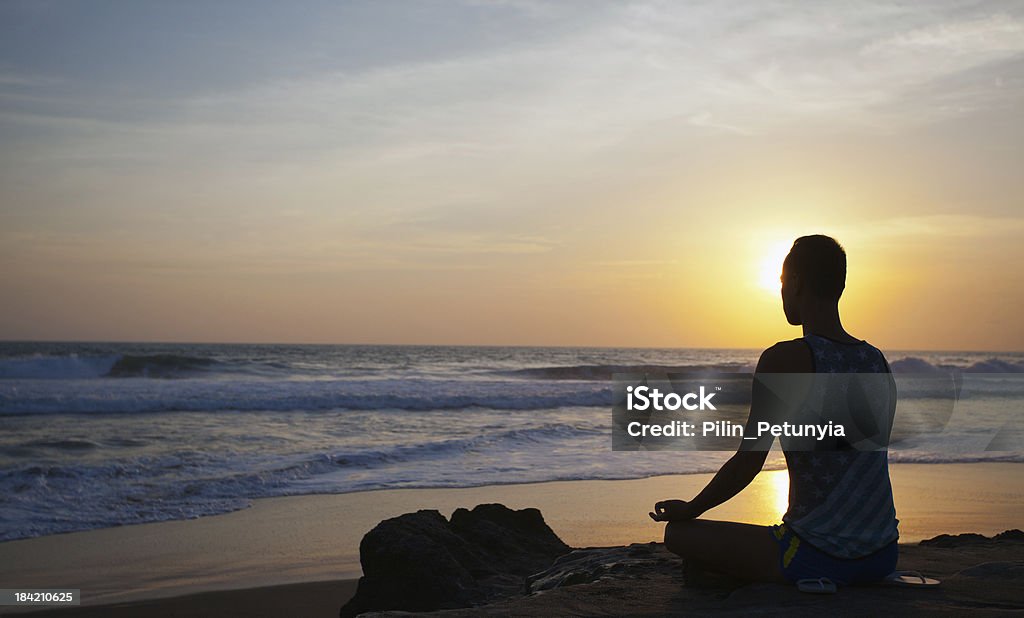 sitting man doing yoga on shore of ocean sitting man doing yoga on shore of ocean, bali, indonesia Adult Stock Photo