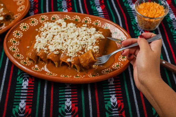 Person eating enchiladas with red pipian. Typical Mexican food.