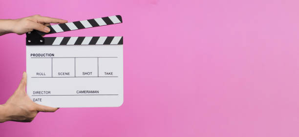 istock Hands are holding a clapper board or movie slate on pink background. 1842148070