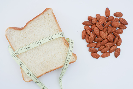 white bread almonds and measuring tape for weight loss and diet concept