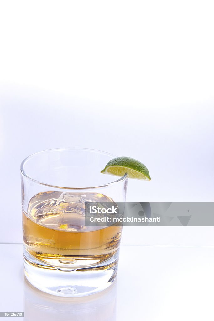 Tumbler with Brown Alcohol and Quartered Lime Wedge Alcohol - Drink Stock Photo