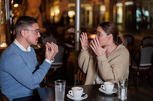 Immerse yourself in the intensity of the moment as a couple becomes engrossed in a heated argument amidst the vibrant ambiance of a bustling cafe