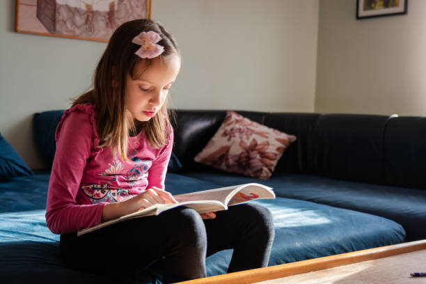 istock Child girl reading a book at home 1842167743