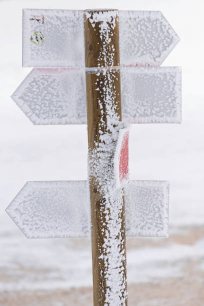istock Frozen road sign with arrows on the mountain. 1842173586
