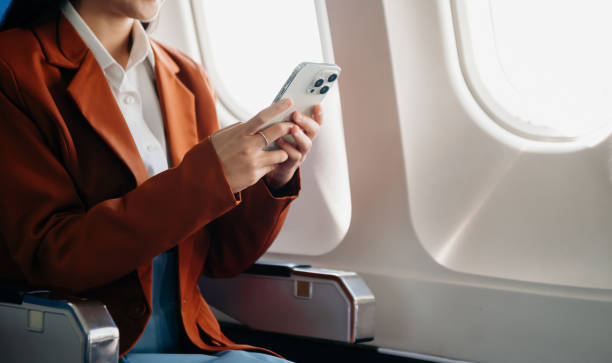 Young Asian executive excels in first class, multitasking with digital tablet, laptop and smartphone. Travel in style, work