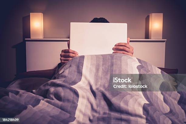 Man Is Sitting In Bed Behind His Laptop Stock Photo - Download Image Now - Adult, Adults Only, Asian and Indian Ethnicities