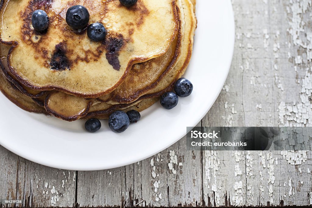 White plate with blueberry pancakes Top view of a stack of blueberry pancakes on a rustic wooden table Antique Stock Photo