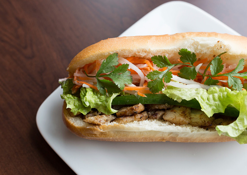 Close-up Vietnamese Bahn mi on white plate and wooden table