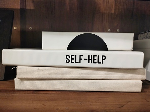 Book on book shelf with text SELF-HELP, concep of self-help book that is written to instruct its readers on solving personal problems - classified as Self-improvement books