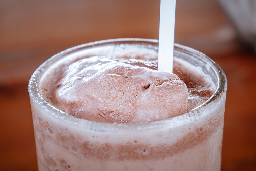 A glass of chocolate milkshake on a wooden table