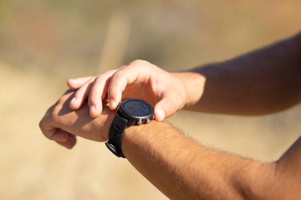 runner on mountain forest trail checking looking at sport watch smartwatch, cross country runner hiker checking performance distance or heart rate pulse sport equipment in use outdoors on summer trail - jogging cross country running hiking outdoors imagens e fotografias de stock