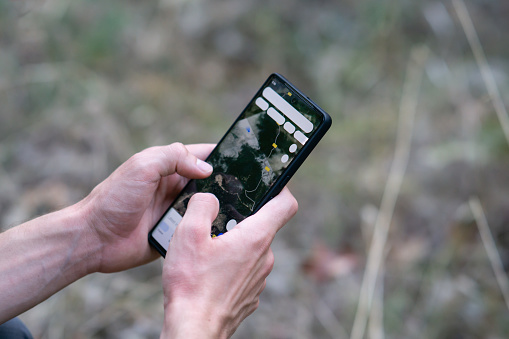 close up of a man using gps navigation app on his smartphone in nature mountain, male hands holding smartphone in nature, man using his smartphone like a navigator in a forest. Close up hands. Hiker using smartphone in the forest