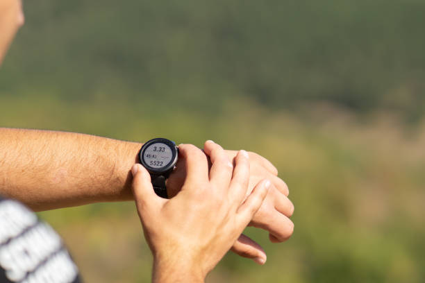 runner on mountain forest trail checking looking at sport watch smartwatch, cross country runner hiker checking performance distance or heart rate pulse sport equipment in use outdoors on summer trail - jogging cross country running hiking outdoors imagens e fotografias de stock