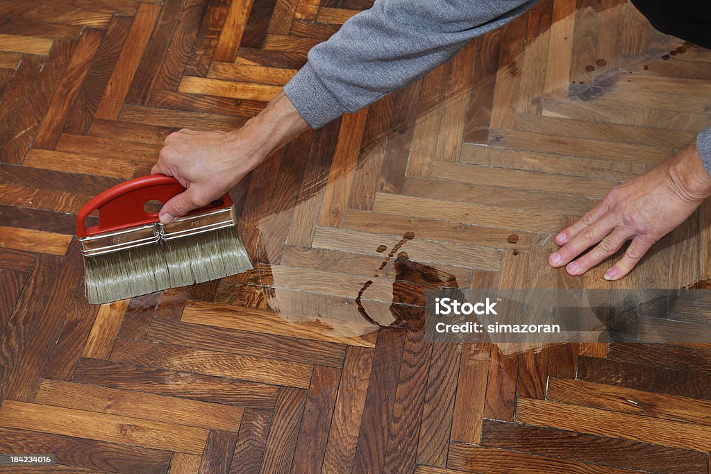 Home renovation Varnishing of oak parquet floor, workers hand and brush Adult Stock Photo