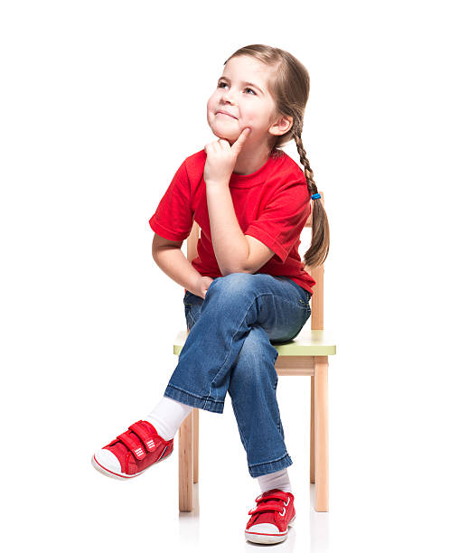 petite fille portant t-short rouge et posant sur une chaise - child contemplation thinking little girls photos et images de collection