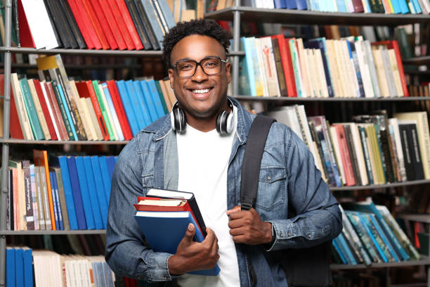 istock Black man holding a stack of books, looking at the camera and smiling broadly 1842363150
