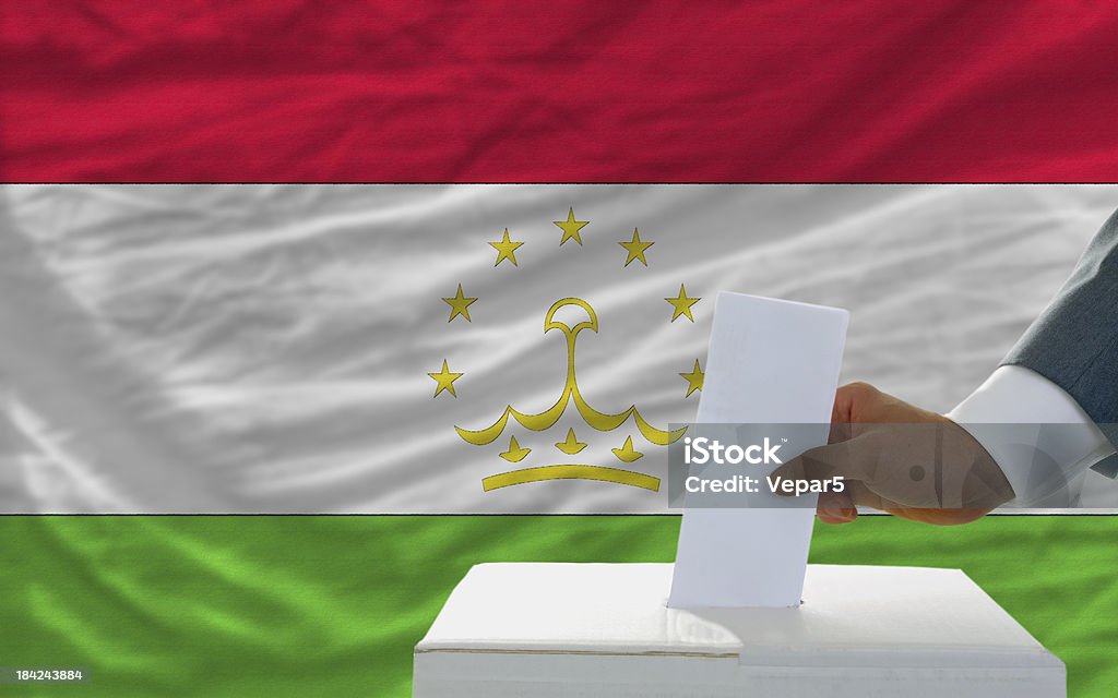 Hombre de voto en las elecciones en Tayikistán front of flag - Foto de stock de Adulto libre de derechos