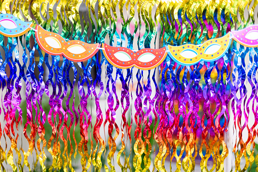 Background featuring a vibrant foil curtains and a string of carnival masks. Carnival party decoration