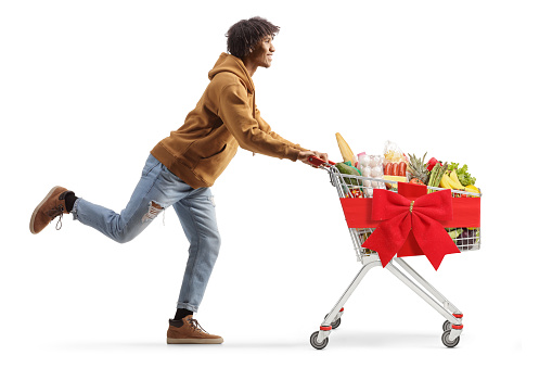 Young african american man running with a shopping cart isolated on white background, christmas shopping concept