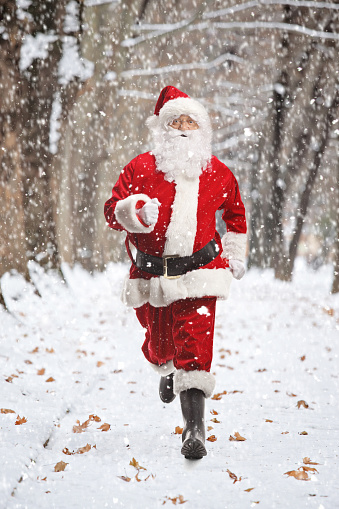 Full length portrait of Santa Claus running on a snowy winter day