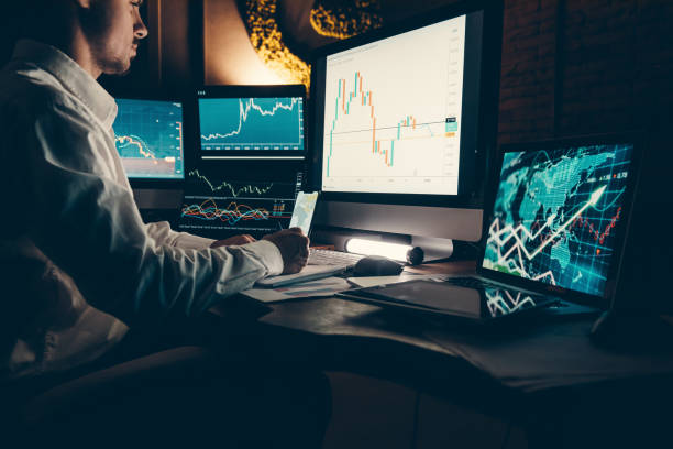 istock Male trader analyzing stock market data while sitting at the office workstation with multiple computers 1842520085