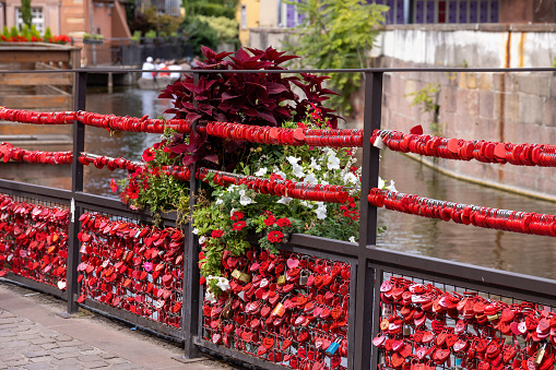 Colmar, France August 15, 2023: Love locks, in red, on the fence by the Lauch river in Colmar, France
