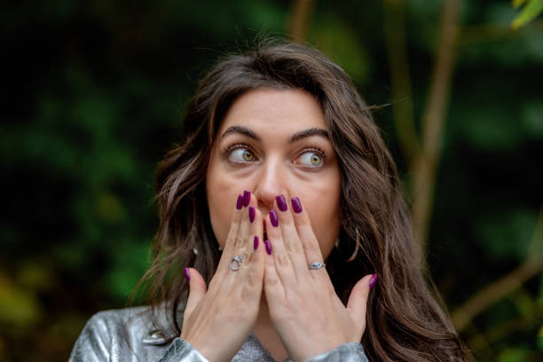 stunned woman covers her mouth with her hands - gasping color image hands covering mouth staring imagens e fotografias de stock