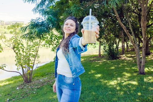 Photo of a young woman in a park holding a plastic cup